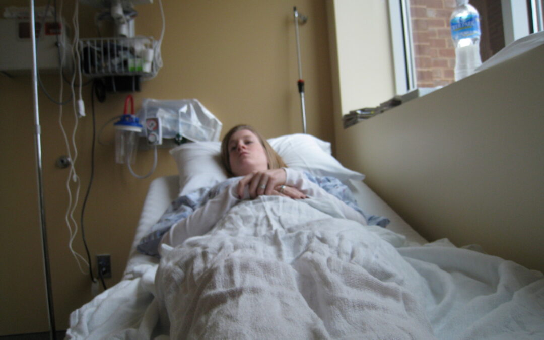 Whitney in a hospital bed after egg retrieval and experiencing Ovarian Hyperstimulation (OHSS)
